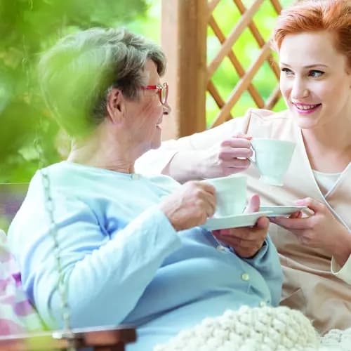 Senior woman drinking tea with a female caregiver. Femme âgée buvant du thé avec une aide-soignante