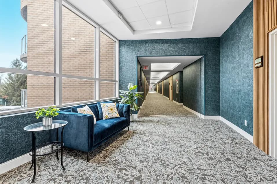 Elegant hallway with blue walls and wood panel details at Chartwell Stillwater Creek / Couloir élégant avec murs bleus et détails en bois à Chartwell Stillwater Creek