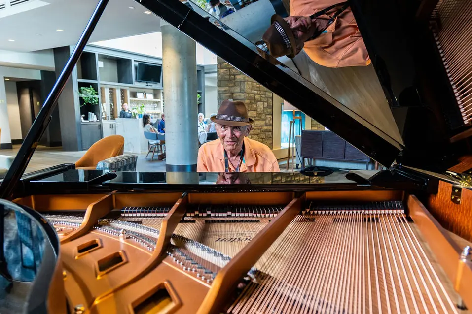 Senior man sitting in front of a grand piano at Chartwell The Edward / Un homme âgé assis devant un piano à queue à Chartwell The Edward
