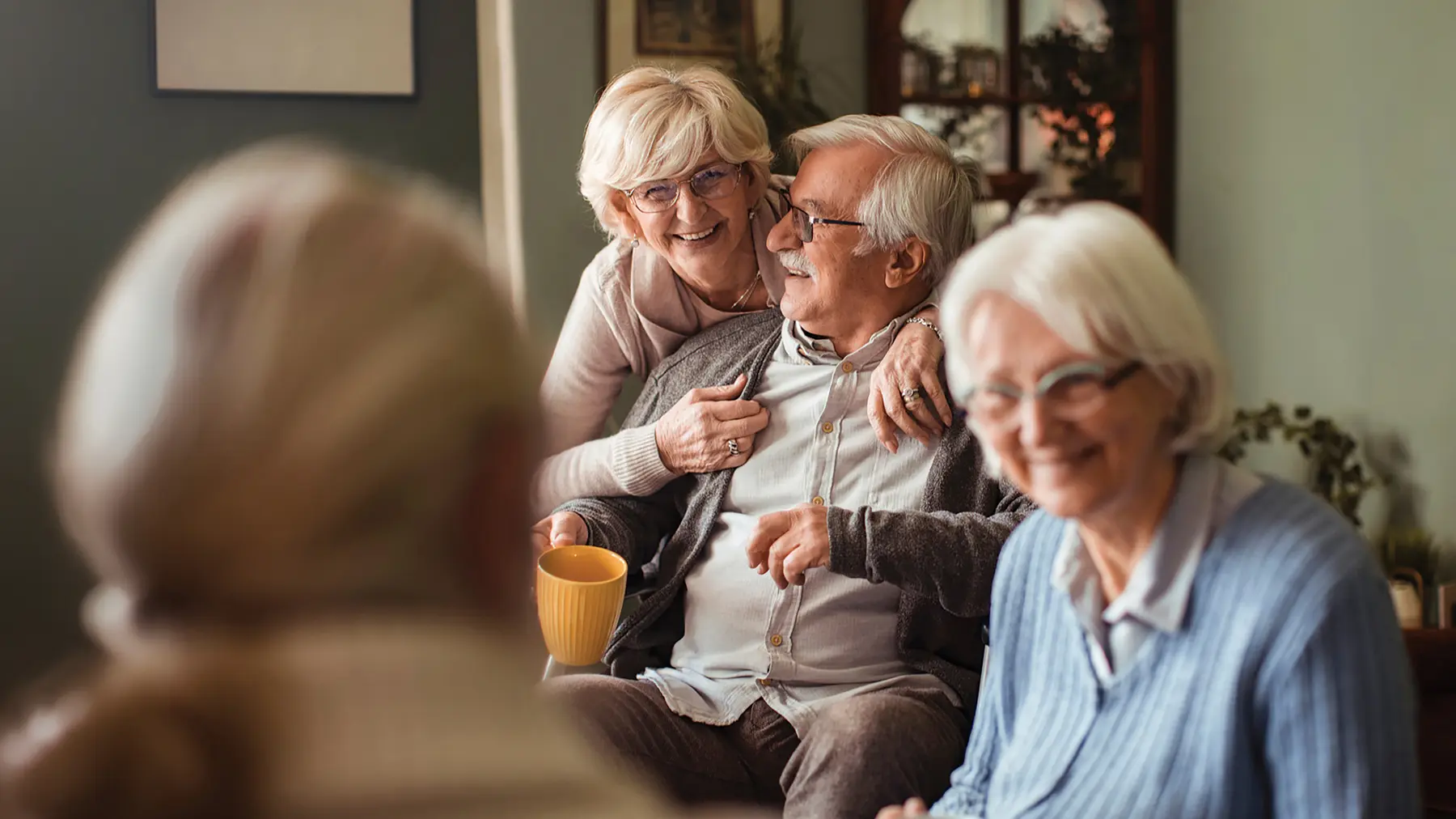 Happy senior friends having coffee and conversation at home /Des seniors heureux qui prennent un café et discutent chez eux