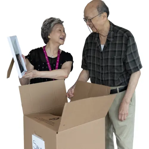 Senior couple are taking out picture frames from their moving box / Un couple âgé sort des cadres photo de leur carton de déménagement