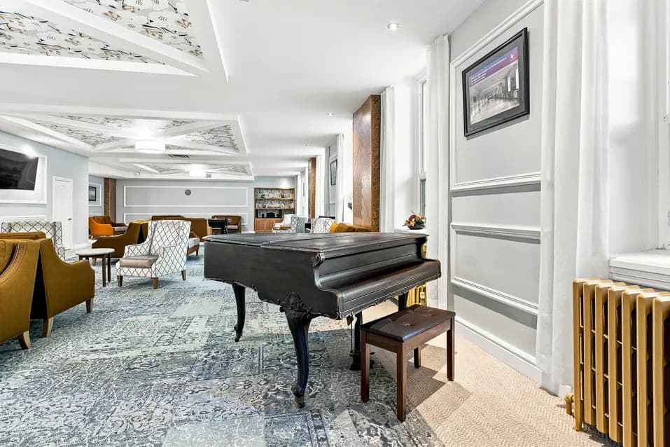 Salon élégant avec piano et aires de détente pour les résidents au Chartwell Monastère d'Aylmer. / Elegant resident lounge with piano and seating areas at Chartwell Monastère d'Aylmer.