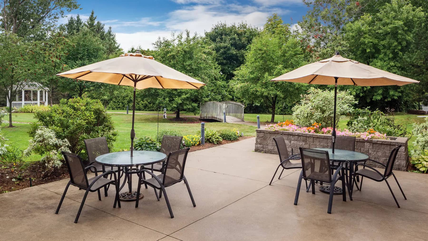 Gorgeous outdoor greenspace with walking paths and patio furniture at Chartwell Barton Retirement Residence.