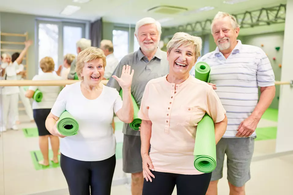 Group of seniors holding exercise mats in a fitness studio after a wellness class / Groupe d’aînés tenant des tapis d’exercice dans un studio d’entraînement après une séance de mieux-être