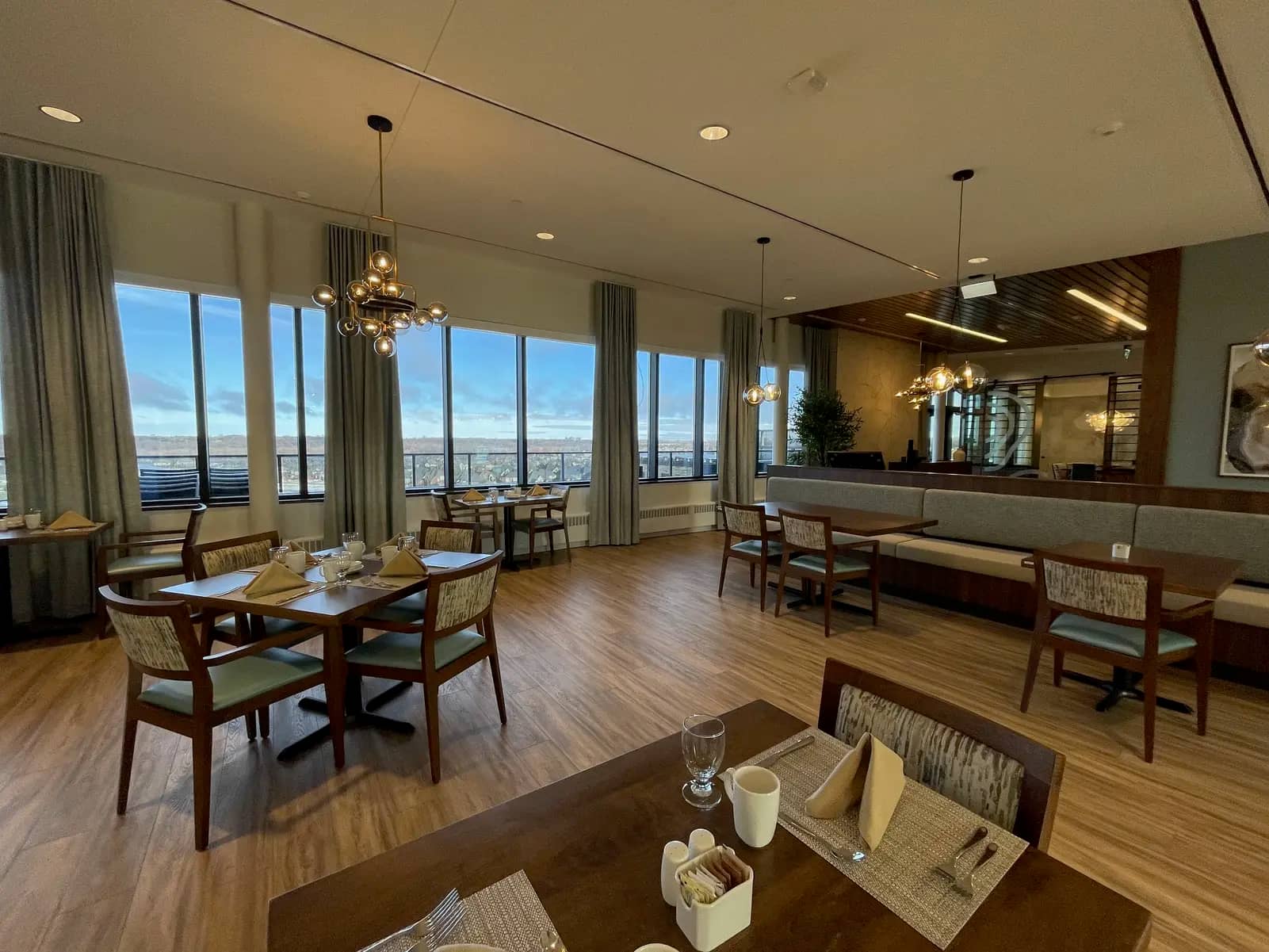 Bright dining room with large windows and modern lighting at Chartwell Riverstone / Salle à manger lumineuse avec grandes fenêtres et éclairage moderne à Chartwell Riverstone