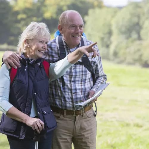 Senior couple wearing hiking gear are out walking on the countryside.