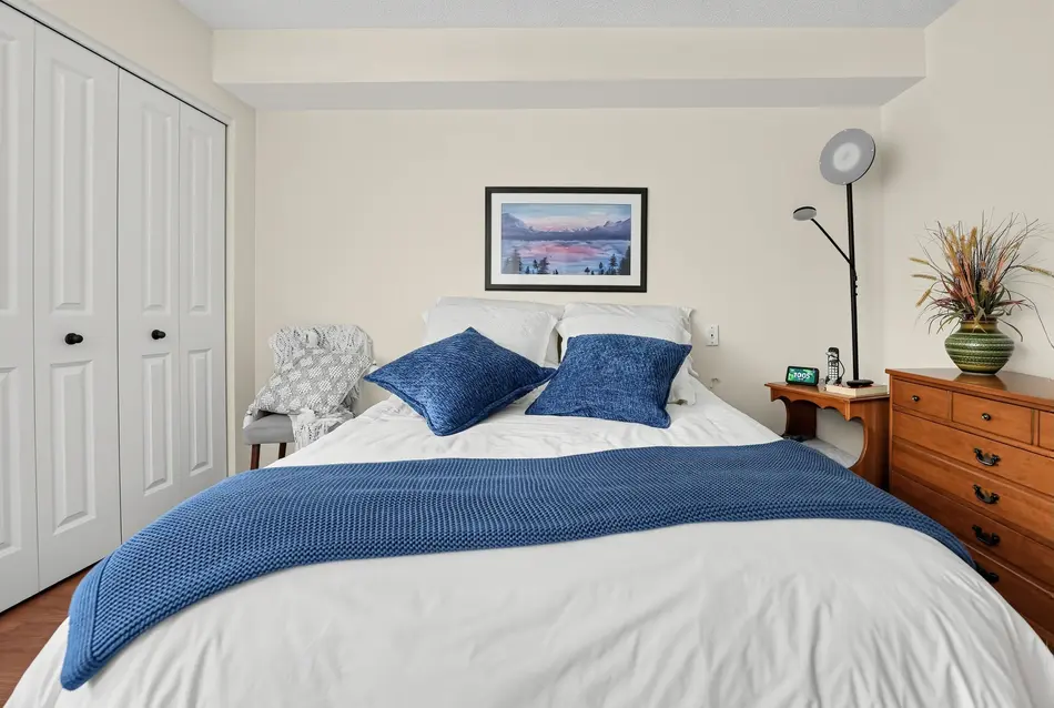 Chambre de la suite modèle avec mobilier classique et literie bleue au Chartwell Seigneuries du Carrefour. / Model suite bedroom with classic furnishings and blue bedding at Chartwell Seigneuries du Carrefour.