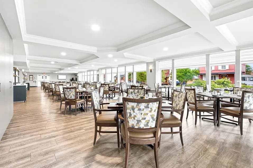 Salle à manger lumineuse avec nombreuses places assises et grandes fenêtres au Chartwell Domaine Notre-Dame. / Bright dining room with ample seating and large windows at Chartwell Domaine Notre-Dame.