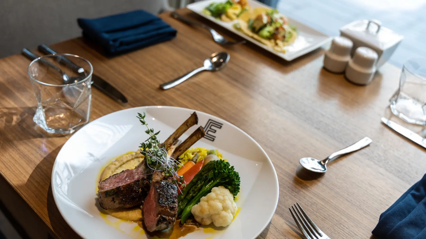 Dining table with lambchop and taco dishes at Chartwell The Edward / Table à manger avec des plats d'agneau et de tacos à Chartwell The Edward