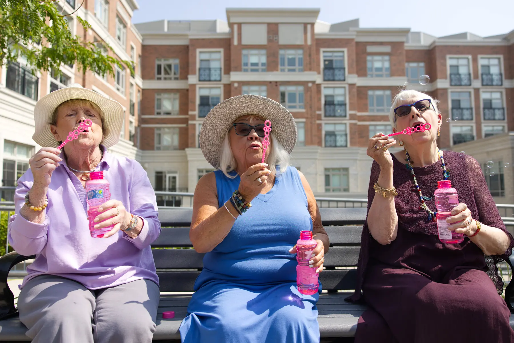 Senior ladies enjoying their time sitting on a bench and blowing the bubbles / Des dames âgées profitent d'un moment de détente, assises sur un banc, en faisant des bulles