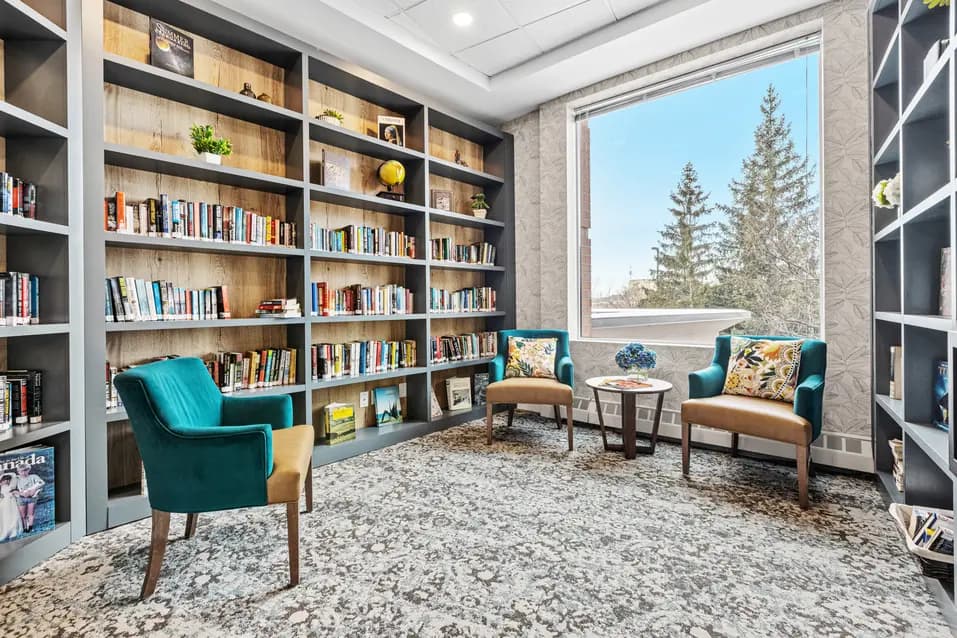 Cozy library with bookshelves and armchairs at Chartwell Stillwater Creek / Bibliothèque confortable avec étagères et fauteuils à Chartwell Stillwater Creek