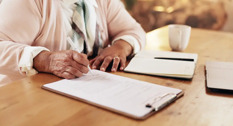 Senior woman signing a document / Femme âgée signant un document