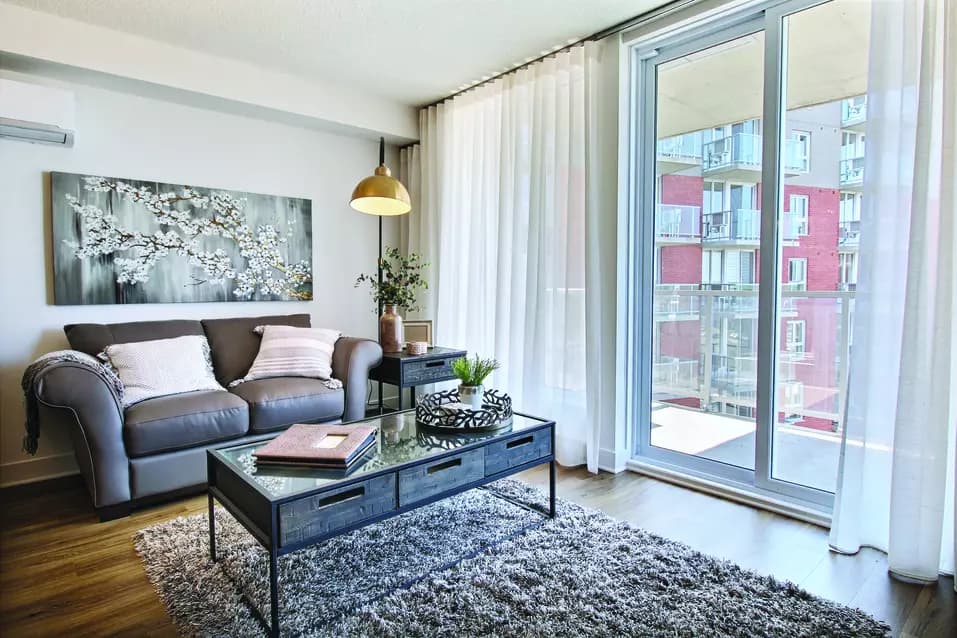 Salon avec grandes fenêtres dans appartement modèle Chartwell Le Montcalm résidences pour retraités retirement residence Model suite living room with large windows
