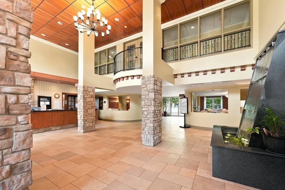 Hall d'entrée avec colonnes de pierre et aire d'accueil au Chartwell Seigneuries du Carrefour. / Entrance lobby with stone columns and welcoming reception area at Chartwell Seigneuries du Carrefour.