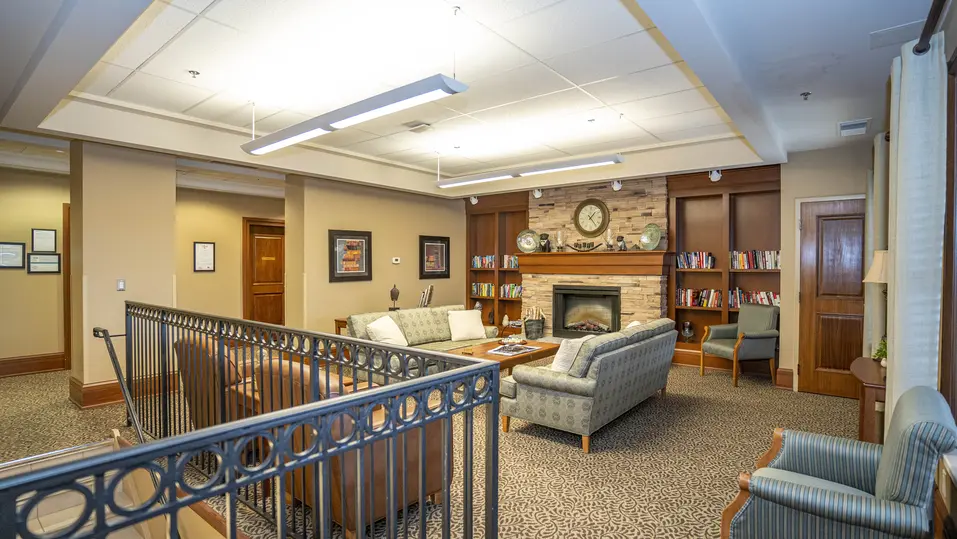 Cozy library lounge with fireplace and bookshelves at Chartwell Westhill / Salon-bibliothèque chaleureux avec foyer et étagères à Chartwell Westhill