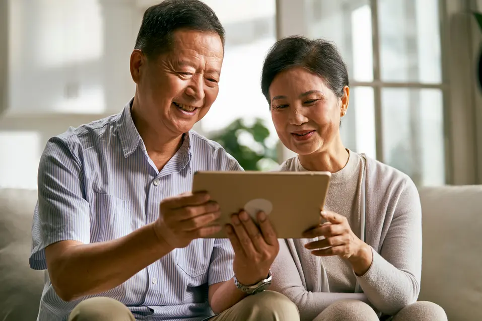Older adults viewing information together on a tablet at home. / Personnes âgées consultant de l’information ensemble sur une tablette à la maison.