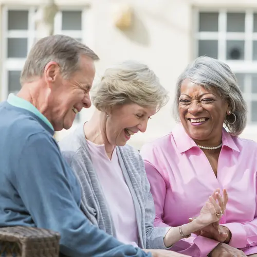 Senior friends are enjoying a fun conversation at the outdoor patio / Des amis seniors discutent joyeusement sur la terrasse extérieure