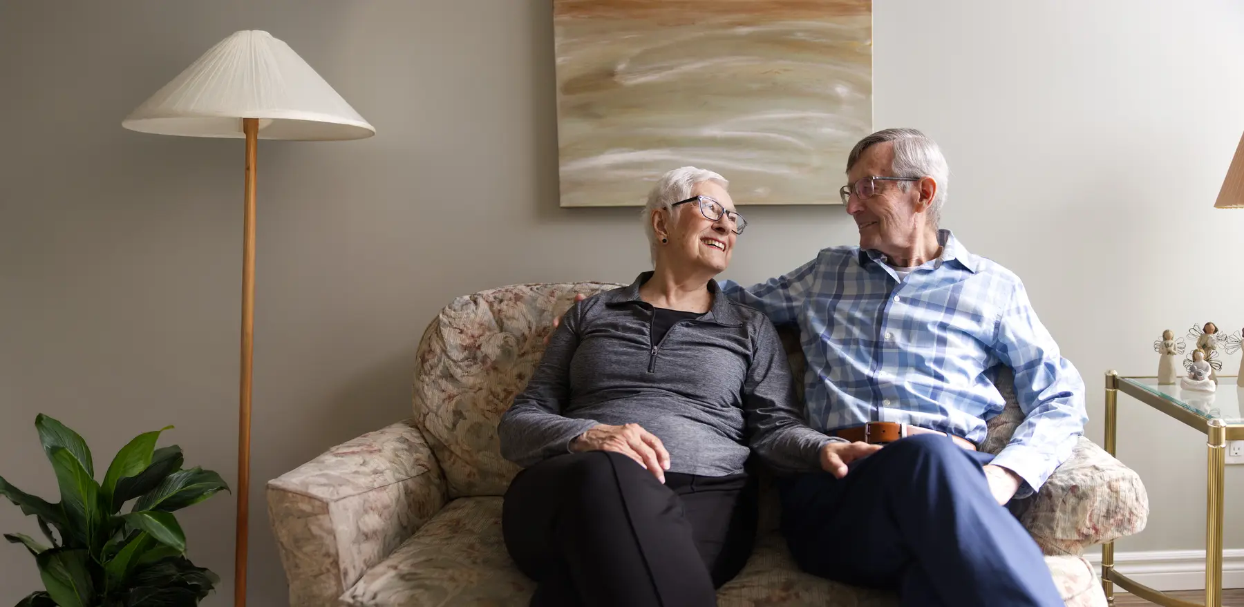 Senior couple is sitting on a cozy sofa in their living room / Un couple âgé est assis sur un canapé confortable dans leur salon