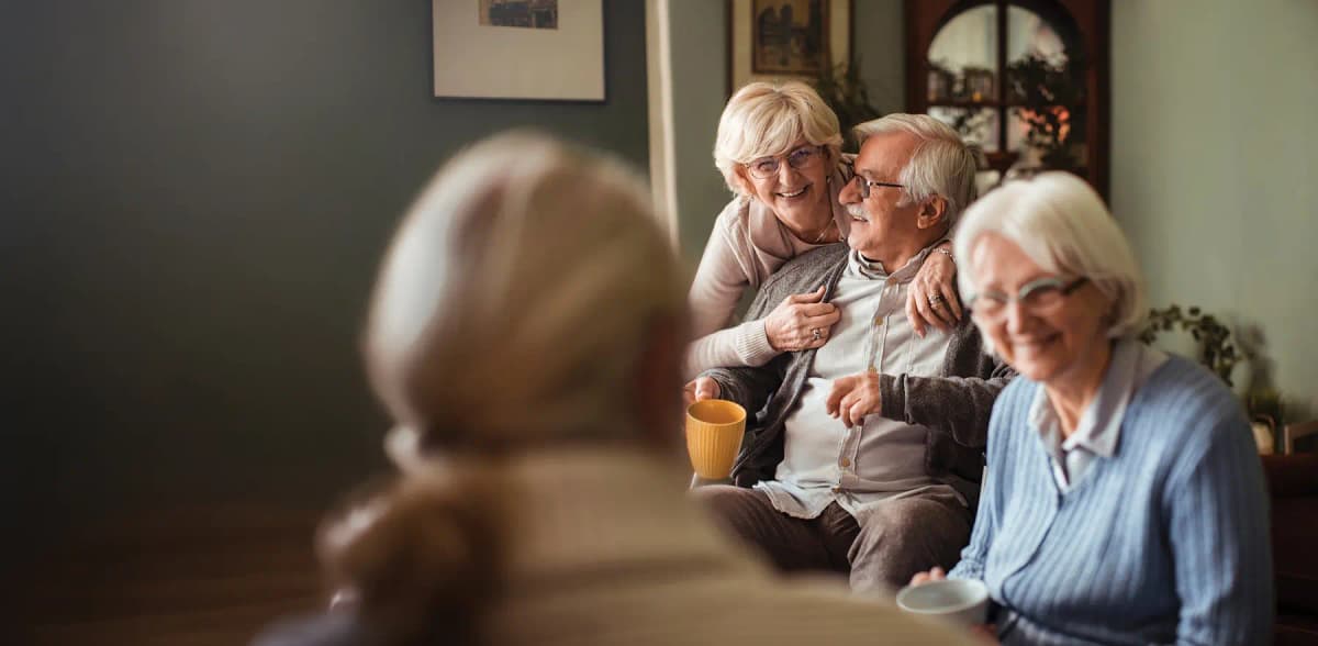 Happy senior friends having coffee and conversation at home