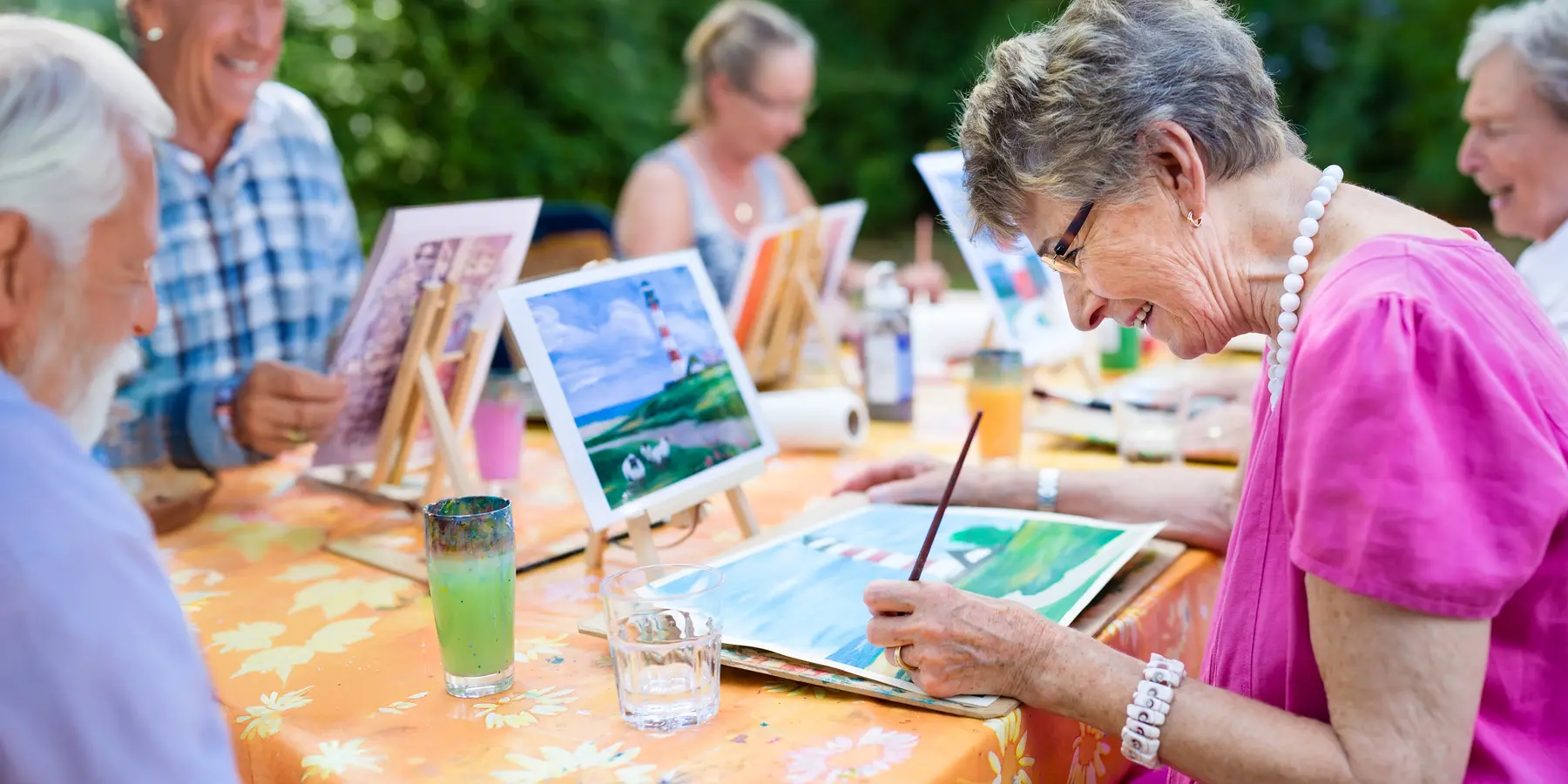 Senior woman is participating an outdoor art class / Une femme âgée participe à un cours d'art en plein air
