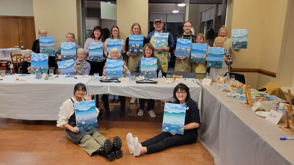 Group of residents displaying their completed landscape paintings / Groupe de résidents montrant leurs peintures de paysage terminées