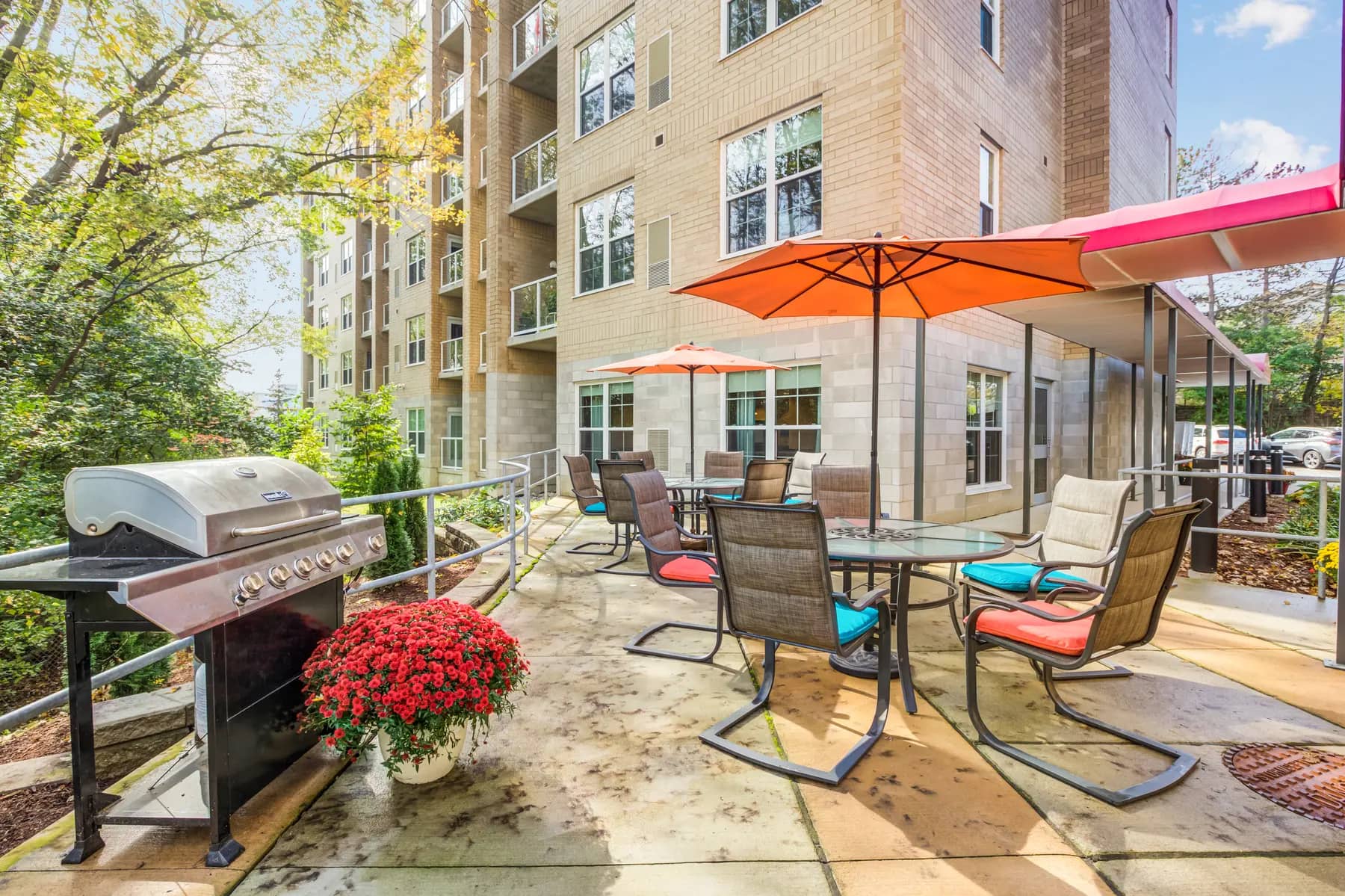 Patio with barbeque grill and parasol tables at Chartwell Bankside senior apartments / Patio avec barbecue et tables avec parasols à Chartwell Bankside, appartements pour seniors