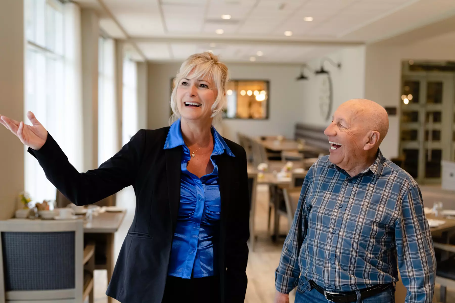 Chartwell staff is showing around the main dining room at a property to a senior / Le personnel de Chartwell fait visiter la salle à manger principale d'une propriété à une personne âgée