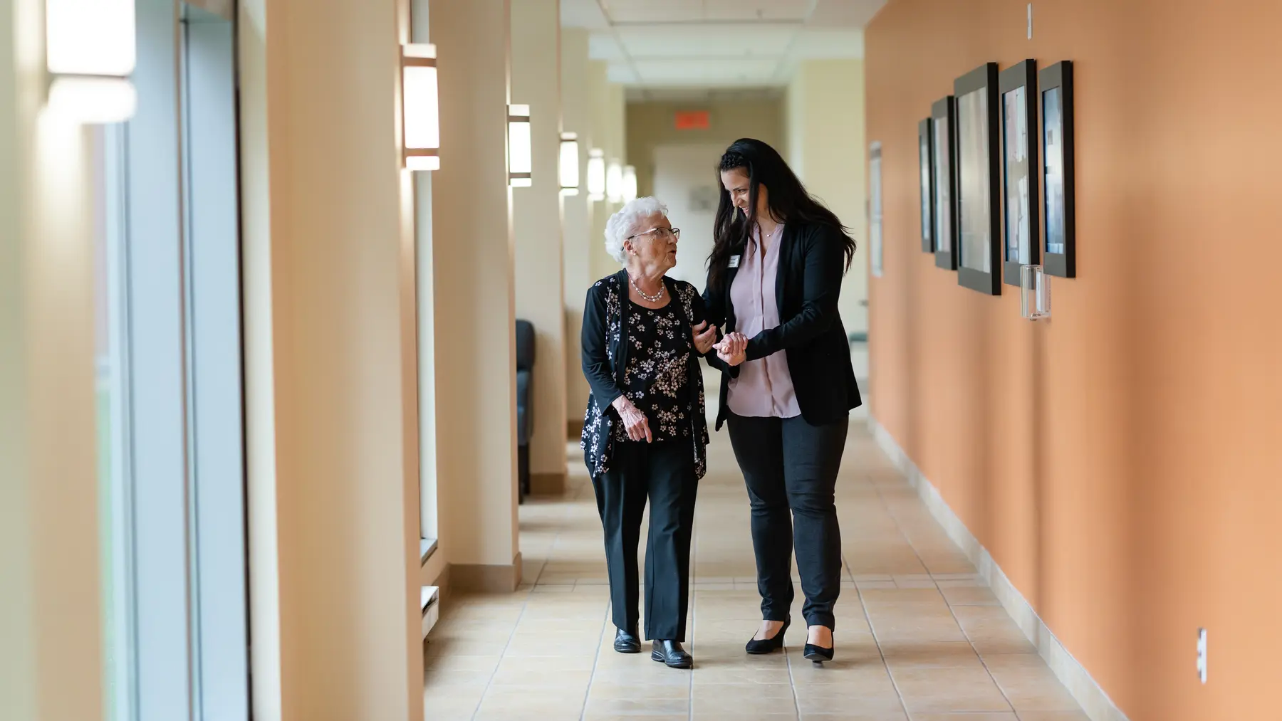 Chartwell care support staff helping a senior resident walk along the corridor