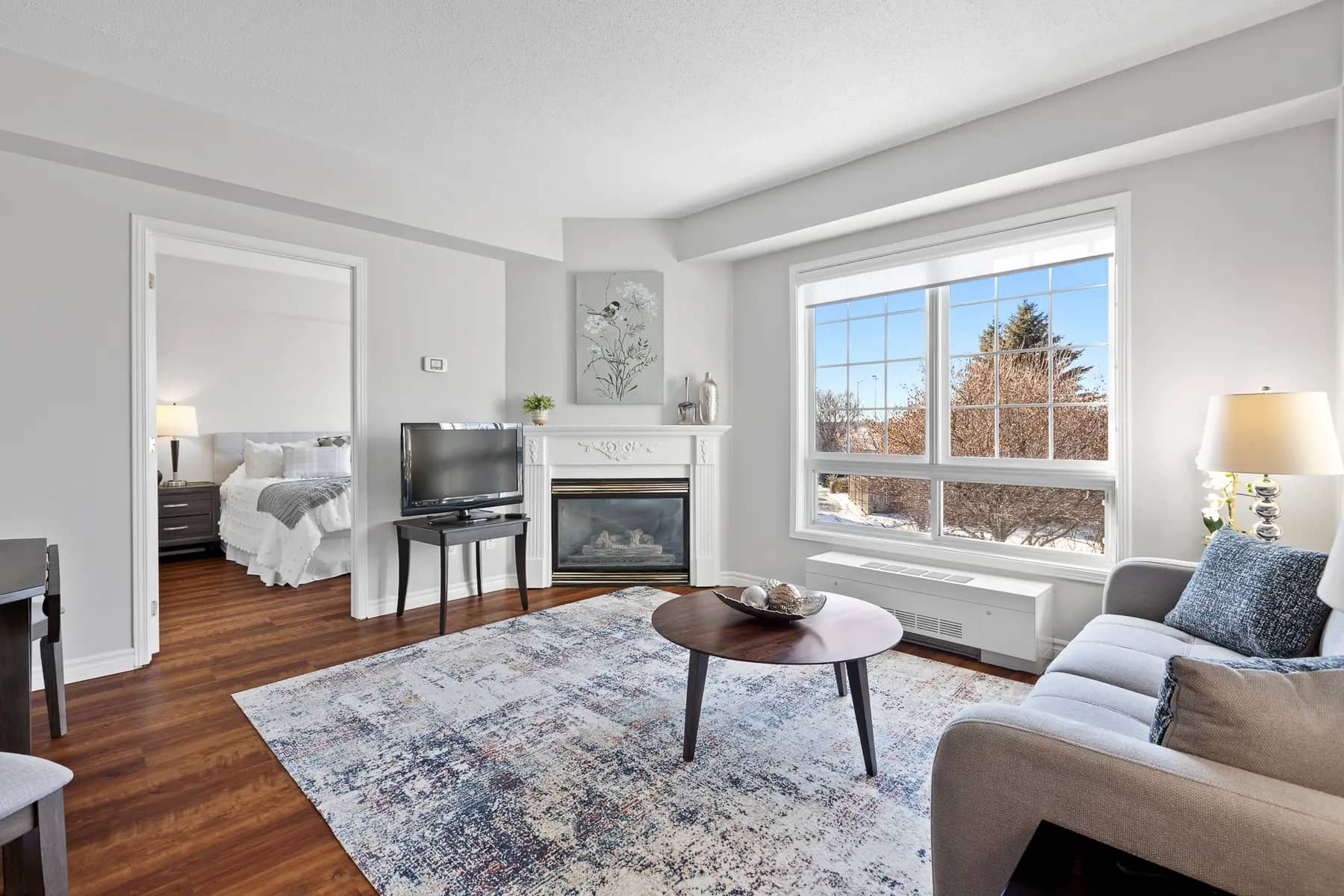 Elegant living room with fireplace and large window at Chartwell Empress Kanata / Salon élégant avec foyer et grande fenêtre à Chartwell Empress Kanata