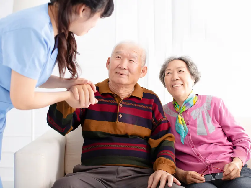 Senior Asian couple sitting on a couch is a care giver, background / Un couple de seniors asiatiques assis sur un canapé est un soignant