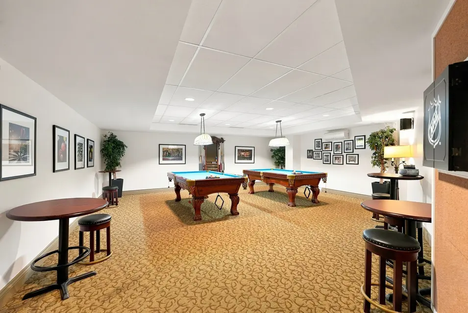 Salle de loisirs avec tables de billard et espaces de rassemblement au Chartwell Seigneuries du Carrefour. / Recreation room with billiards tables and gathering spaces at Chartwell Seigneuries du Carrefour.