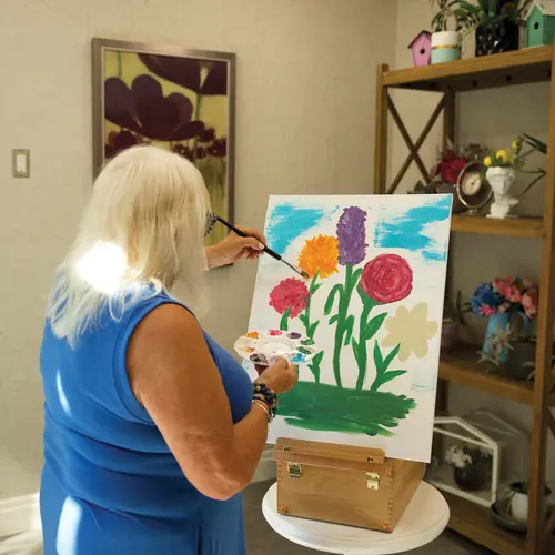 Senior lady paining flowers on a canvas at Chartwell Residence / Une dame âgée peignant des fleurs sur une toile à la résidence Chartwell