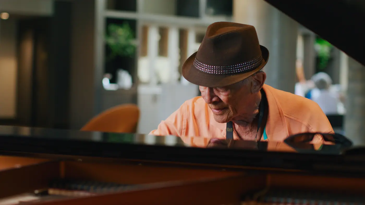 Senior man sitting in front of a grand piano at Chartwell The Edward / Un homme âgé assis devant un piano à queue à Chartwell The Edward
