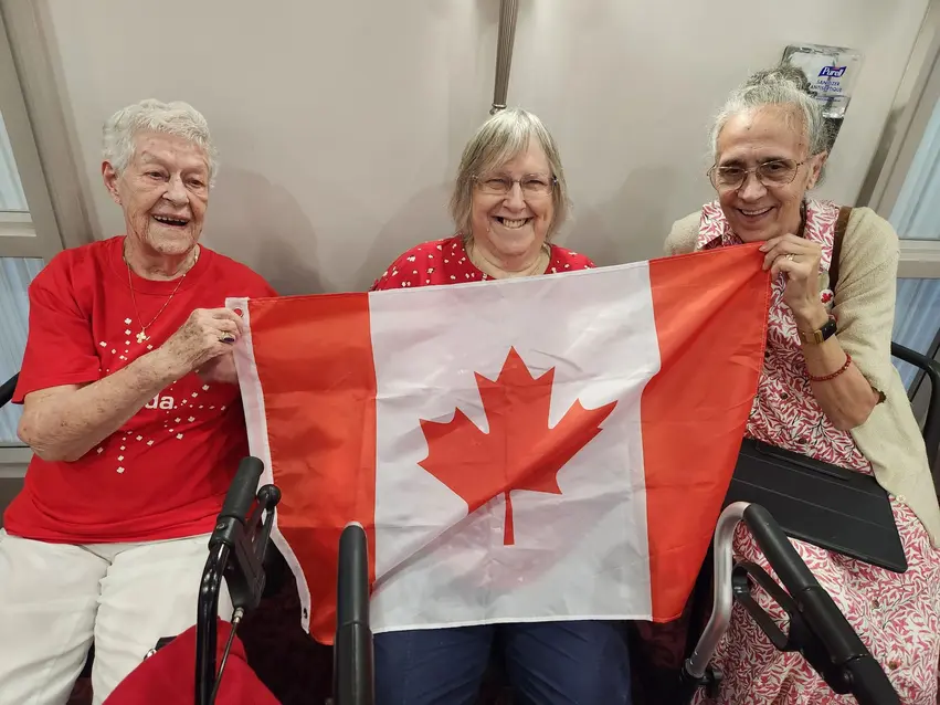 Residents at Chartwell Robert Speck posing while holding the Canadian flag / Résidents de Chartwell Robert Speck posant en tenant le drapeau canadien