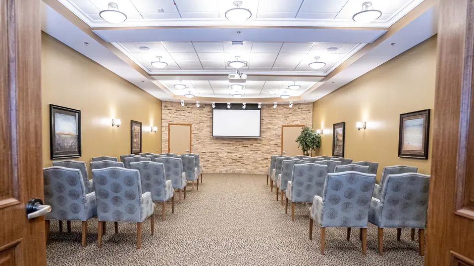 Theatre room with rows of upholstered chairs at Chartwell Westhill / Salle de théâtre avec rangées de fauteuils rembourrés à Chartwell Westhill