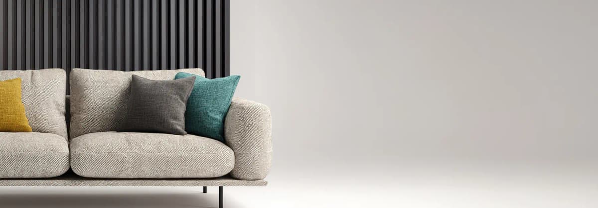Sofa with three coloured cushion in front of the dark grey wood panel wall / Canapé avec trois coussins colorés devant un panneau mural en bois gris foncé