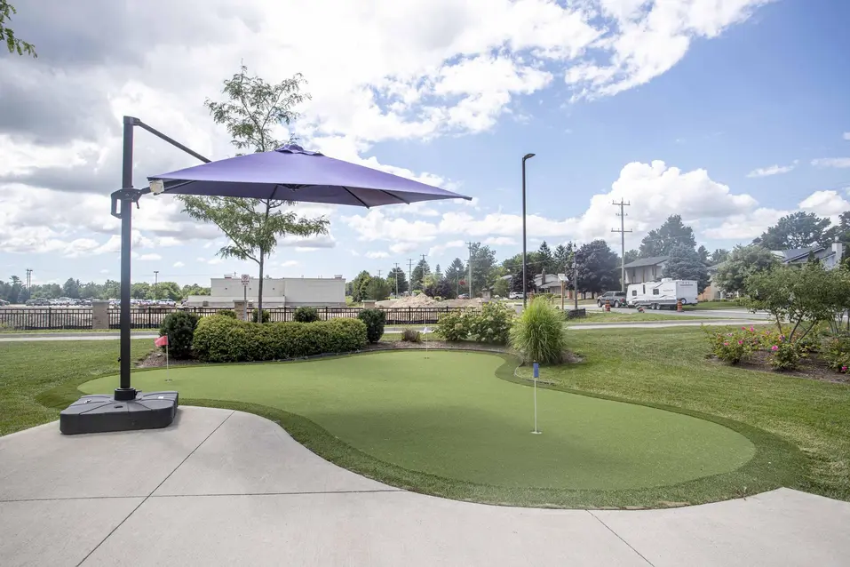 Outdoor putting green with purple umbrella at Chartwell Dorchester Terrace / Terrain de golf miniature extérieur avec parasol à Chartwell Dorchester Terrace