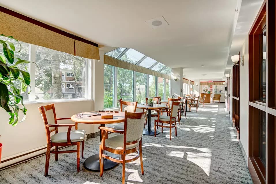 Verrière avec table et chaises pour lecture jeux casse-tête Chartwell Manoir Archer résidence pour retraités