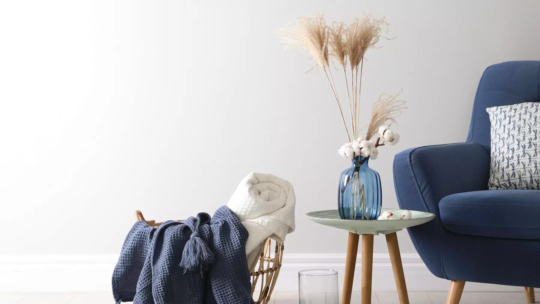 Livingroom with blue chair, side table and basket with knitted blanket. Salon avec chaise bleue, table d'appoint et panier avec couverture tricotée