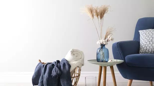 Livingroom with blue chair, side table and basket with knitted blanket. Salon avec chaise bleue, table d'appoint et panier avec couverture tricotée