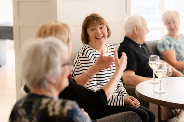 Senior residents chatting and enjoying a glass of wine