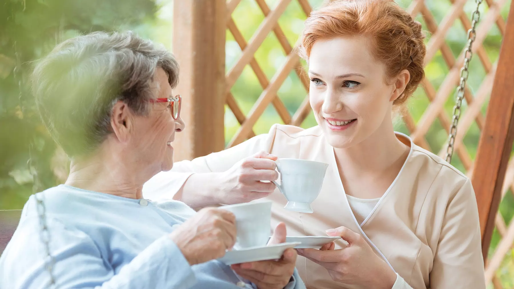 Senior woman drinking tea with a female caregiver. Femme âgée buvant du thé avec une aide-soignante
