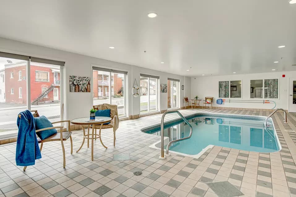 Piscine intérieure avec grandes fenêtres tables et chaises Chartwell Notre-Dame de Victoriaville résidence pour retraités