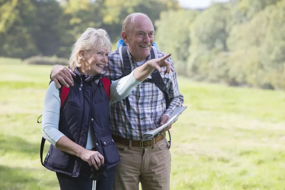 Senior couple wearing hiking gear are out walking on the countryside.