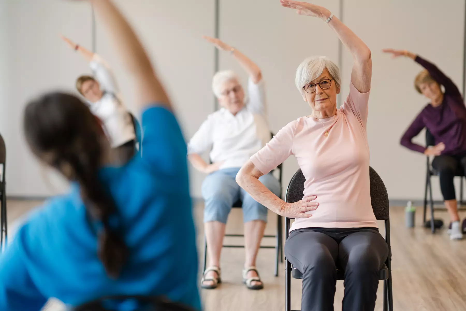 Senior residents performing chair yoga on chair with the instructor