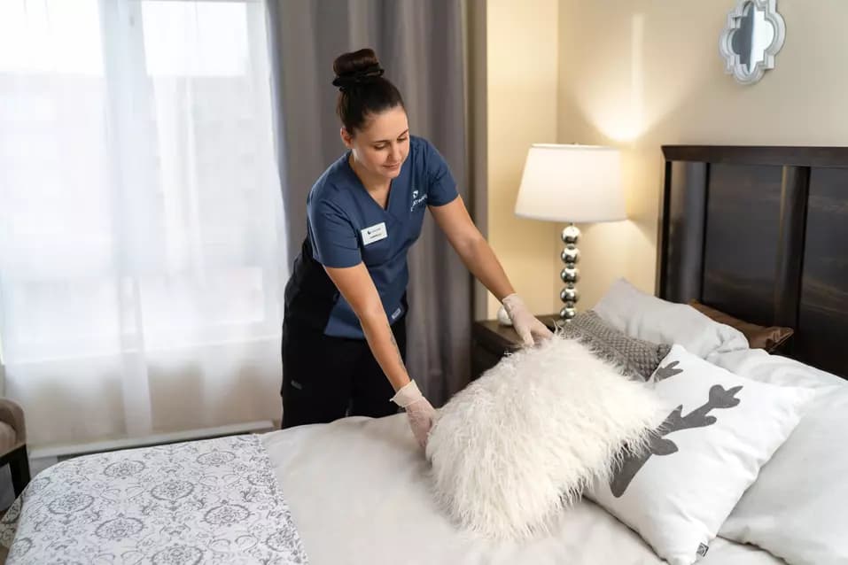 Housekeeper at Chartwell retirement residence is organizing a bed for resident / L'aide ménagère de la maison de retraite Chartwell organise un lit pour un résident