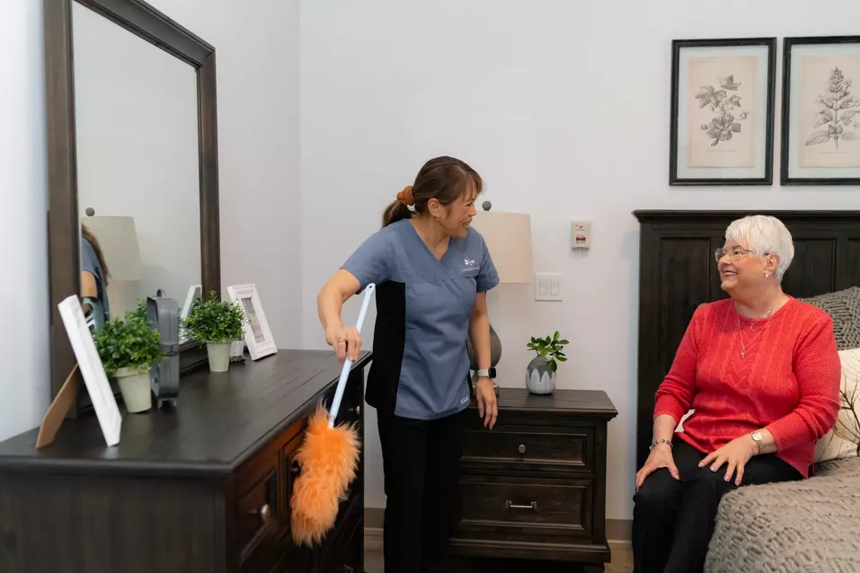 Chartwell staff is having a light conversation with a residence while cleaning the residence's room / Le personnel de Chartwell a une conversation légère avec un résident pendant qu'il nettoie sa chambre