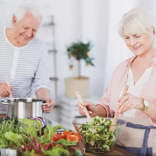 senior couple preparing a meal and salad in a kitchen